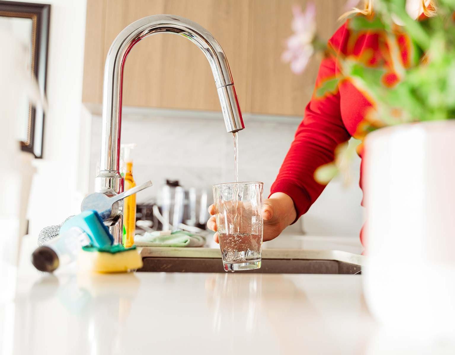 Someone filling a glass of water from the kitchen tap.